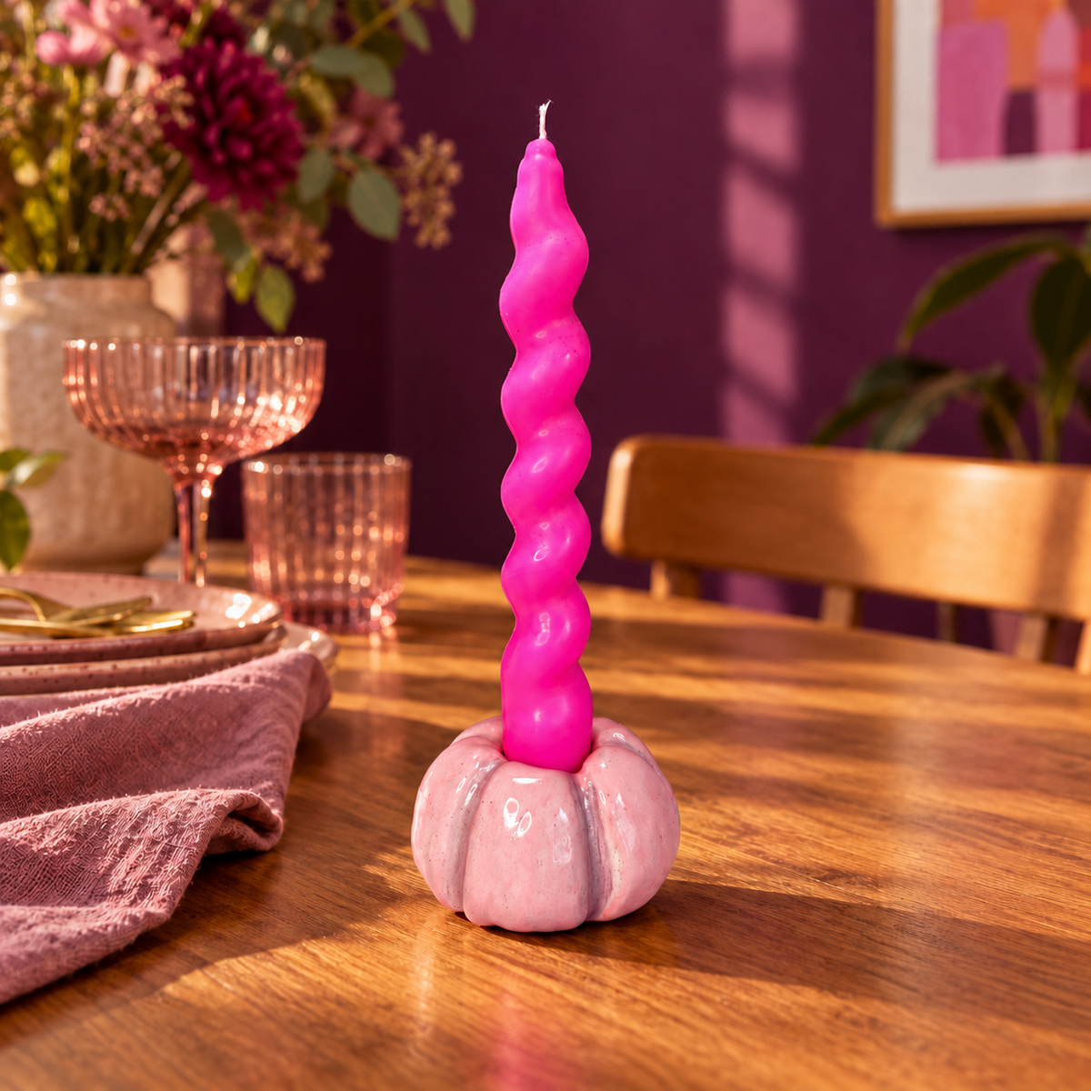 Light pink ceramic pumpkin taper holder with mauve groove details holding a neon pink twist taper on a timber dining table. Candle sold separately.