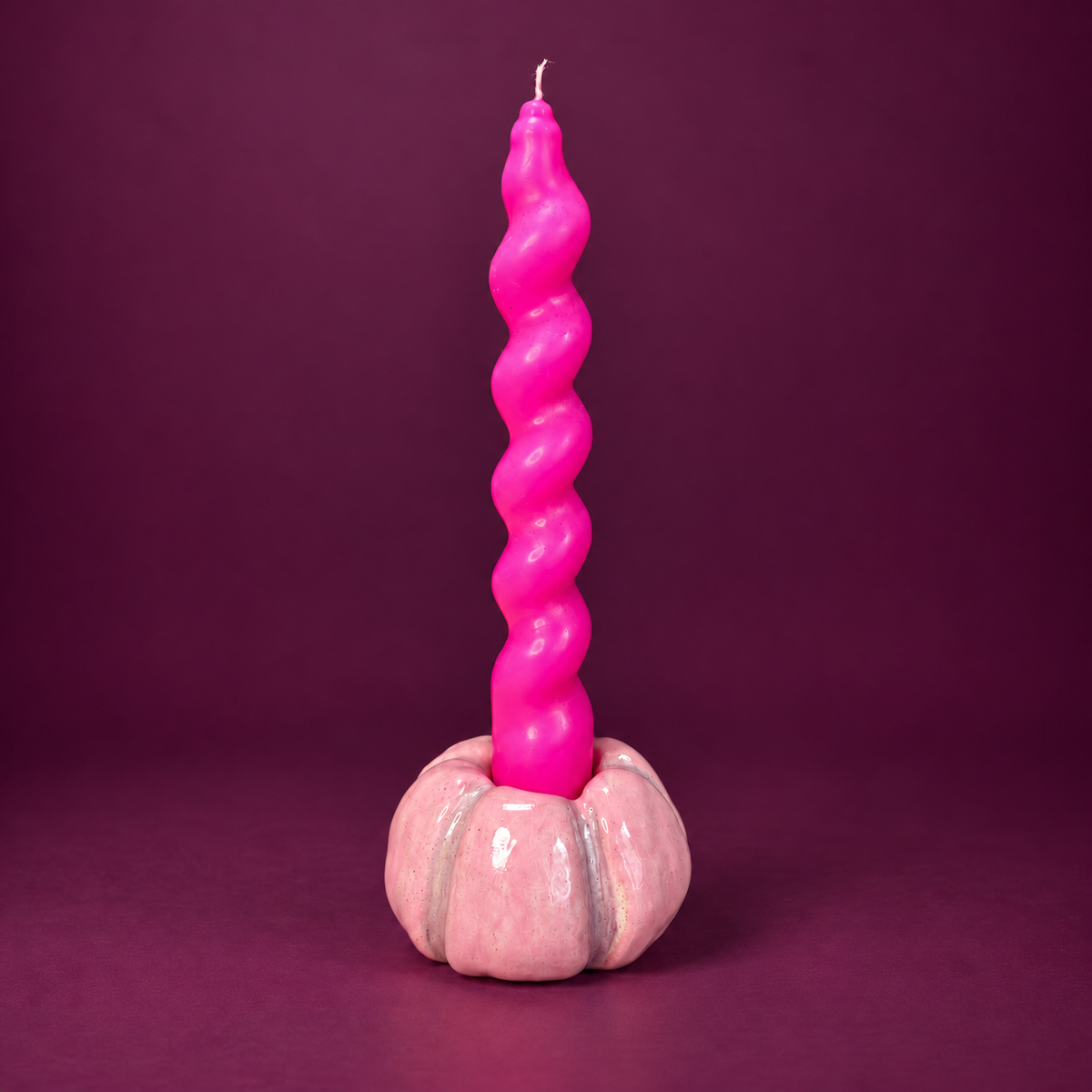 Light pink pumpkin taper holder with mauve details and a neon pink twist taper against a plum background. Candle sold separately.